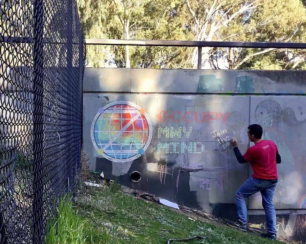 Chalk Wall: Man chalking 'Occupy MWy Mind'